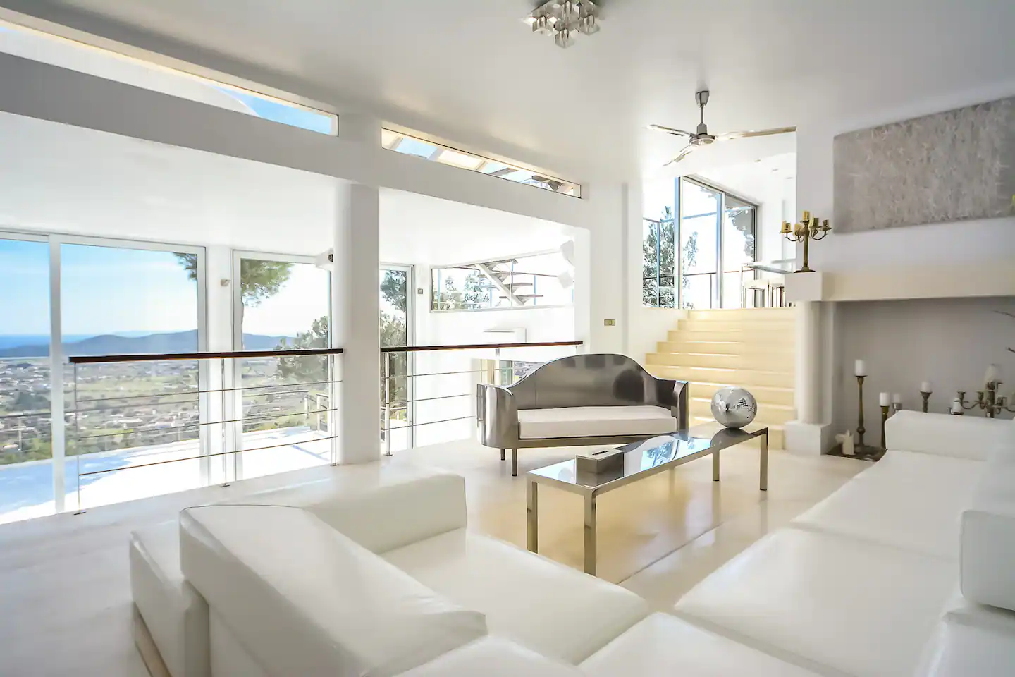 A chic living room with modern decor, featuring a stylish sofa, artistic coffee table, and large windows offering a scenic city view.